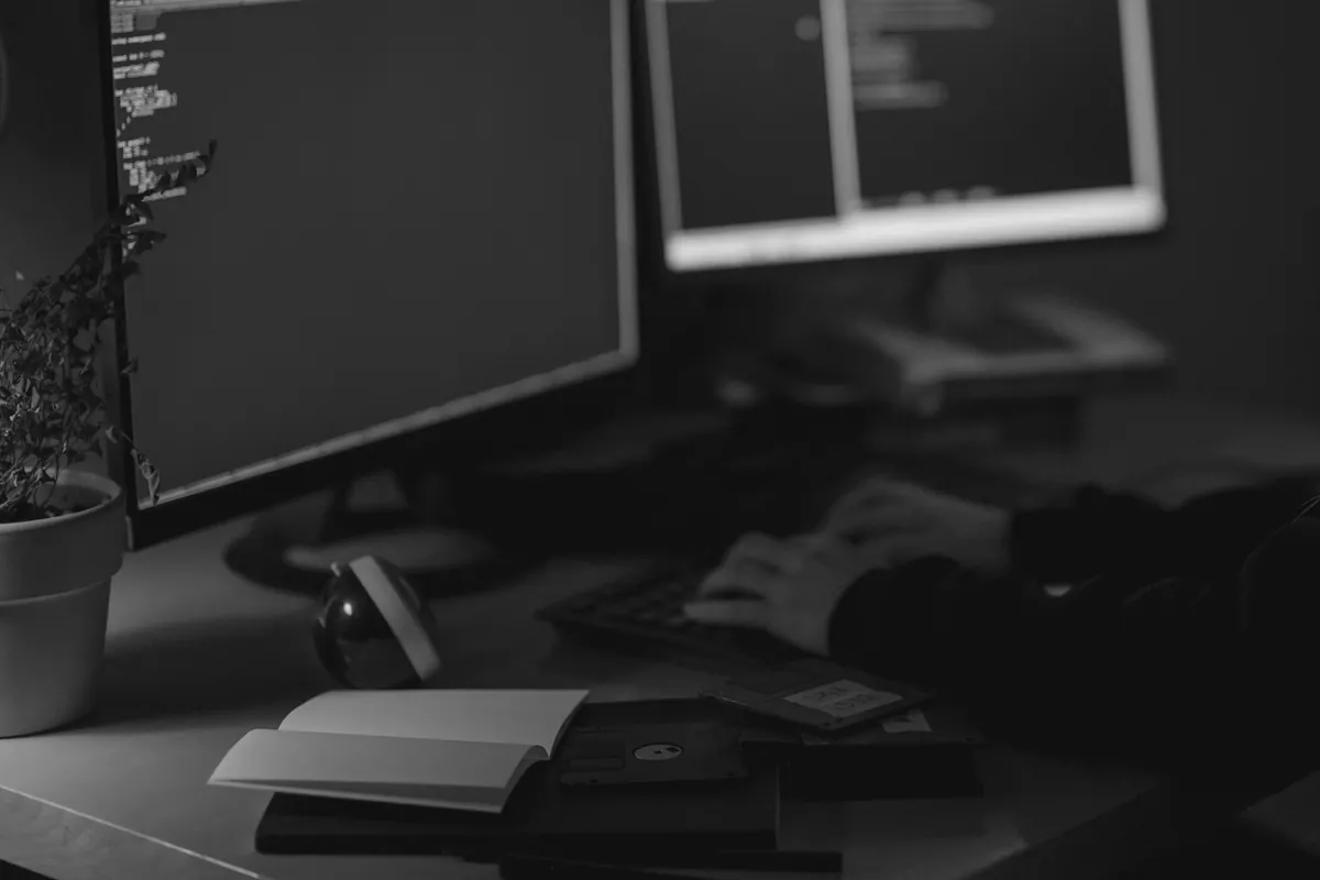 Developer working at two monitors in a dim room