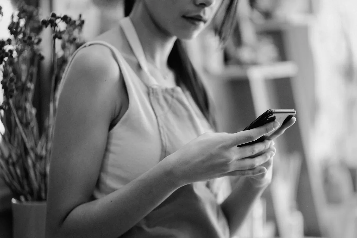 Florist in an apron checking her phone at work