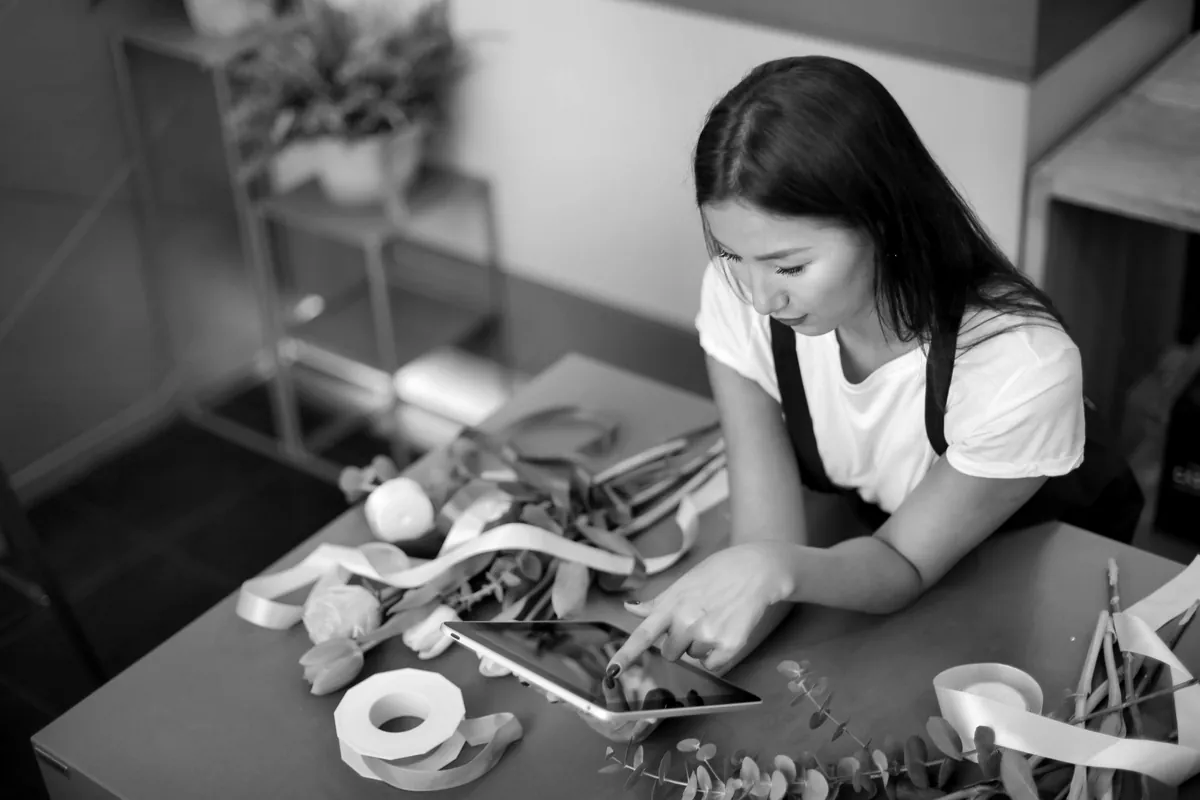 Florist checking a tablet while arranging flowers in her shop