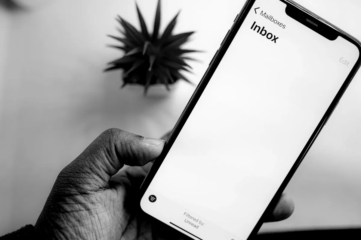 Hand holding a phone showing an email inbox