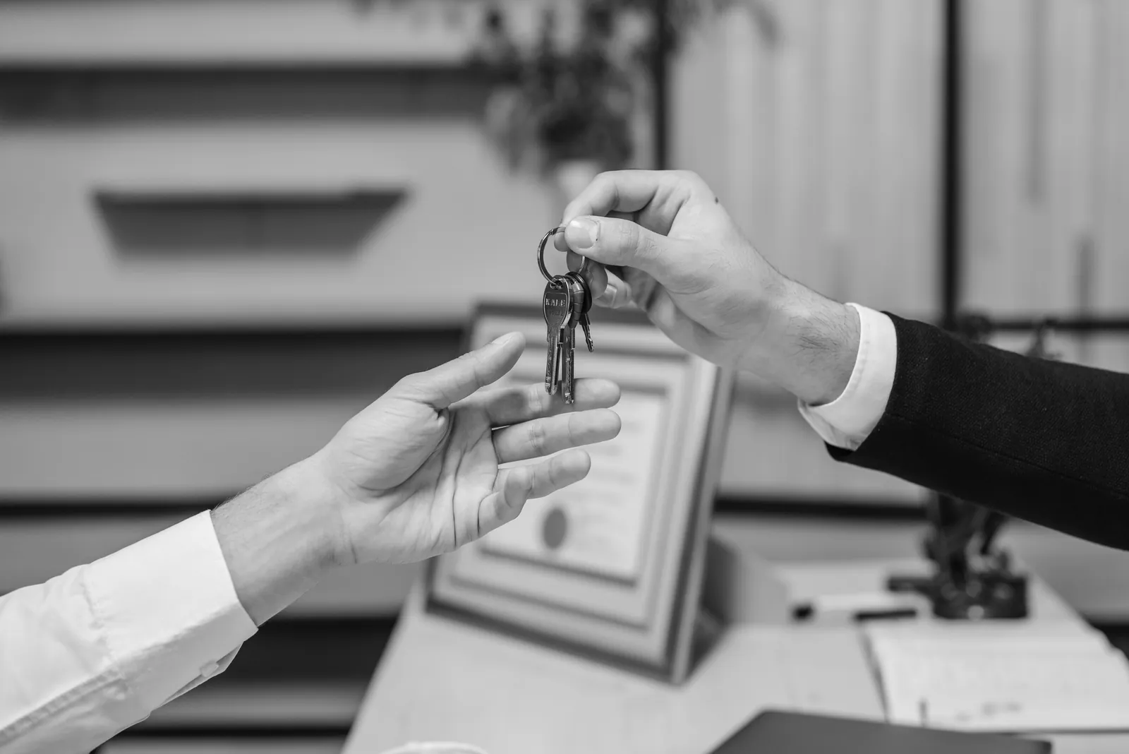 One person handing a set of keys to another across a desk