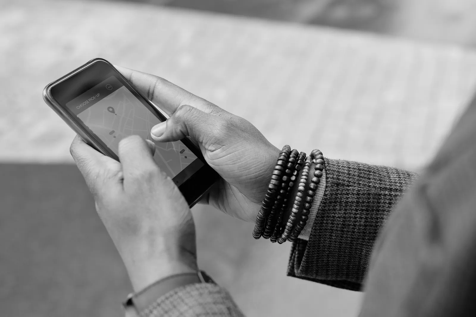 Hands holding a smartphone that shows a navigation app outdoors