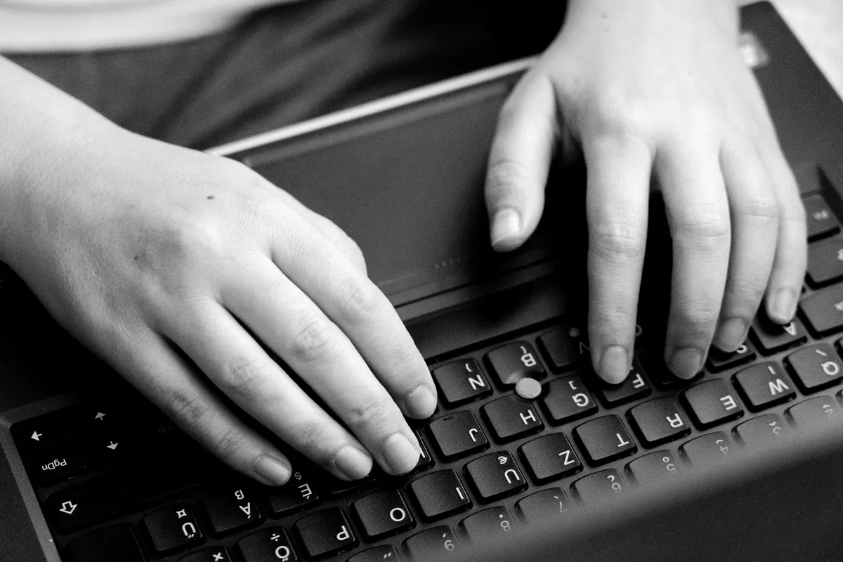 Hands typing on a laptop keyboard