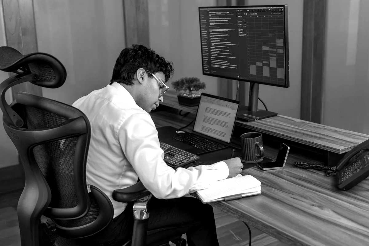 Man at a desk reviewing rows of data on a monitor