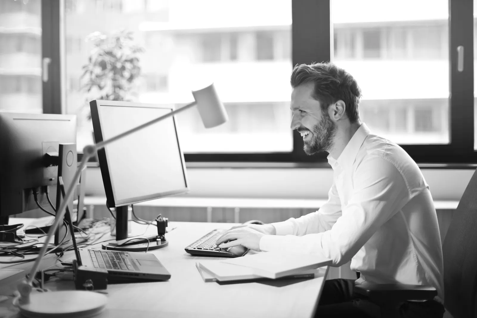 Man working at an office desk with a computer in daylight