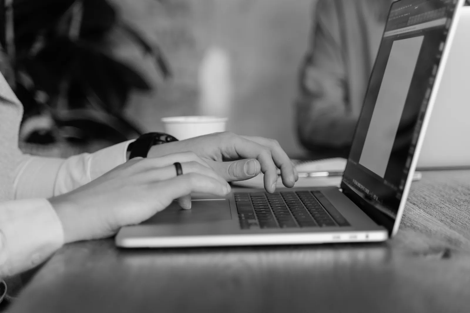 Person typing on a laptop at a wooden table