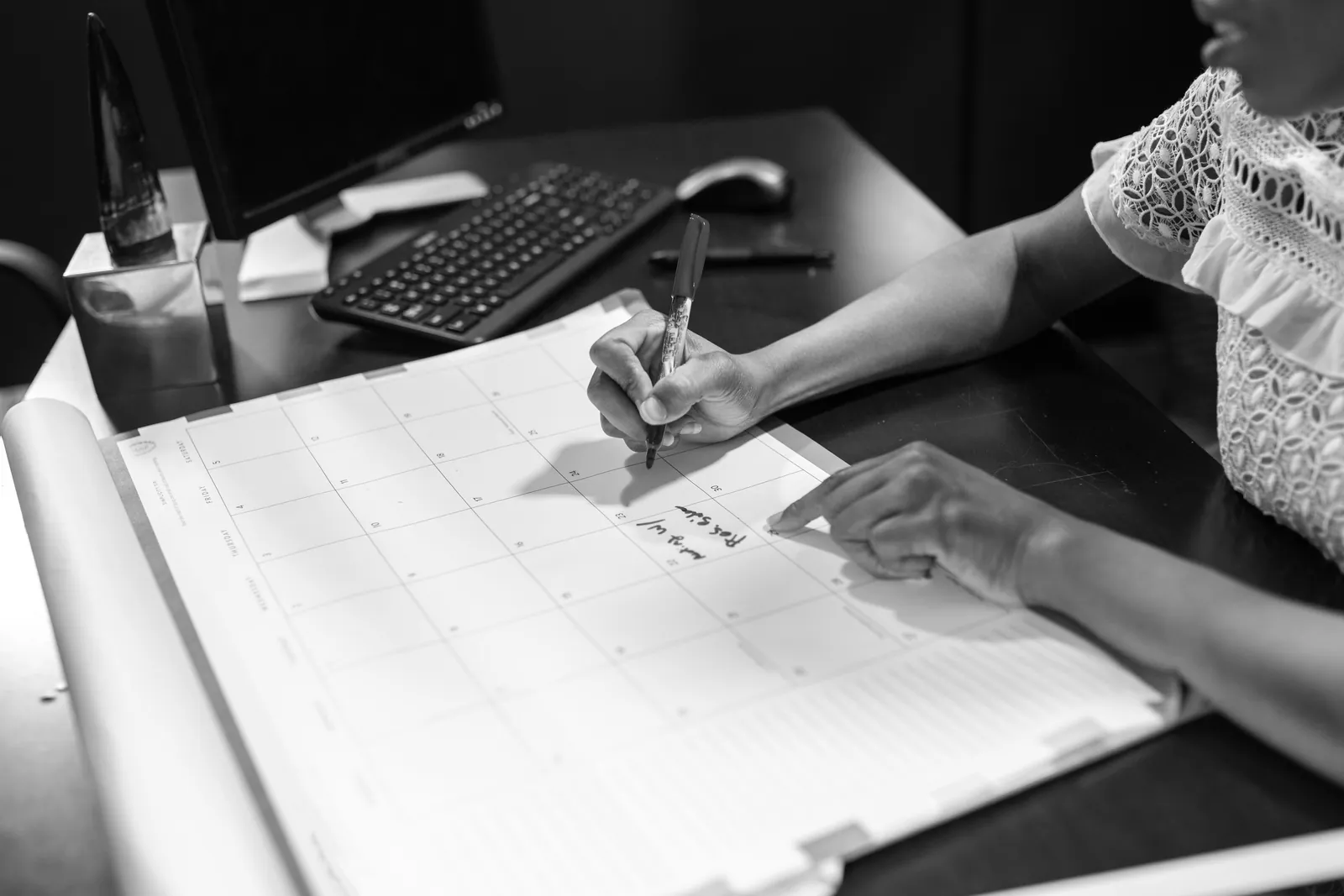 Person writing a note in a desk calendar with a pen