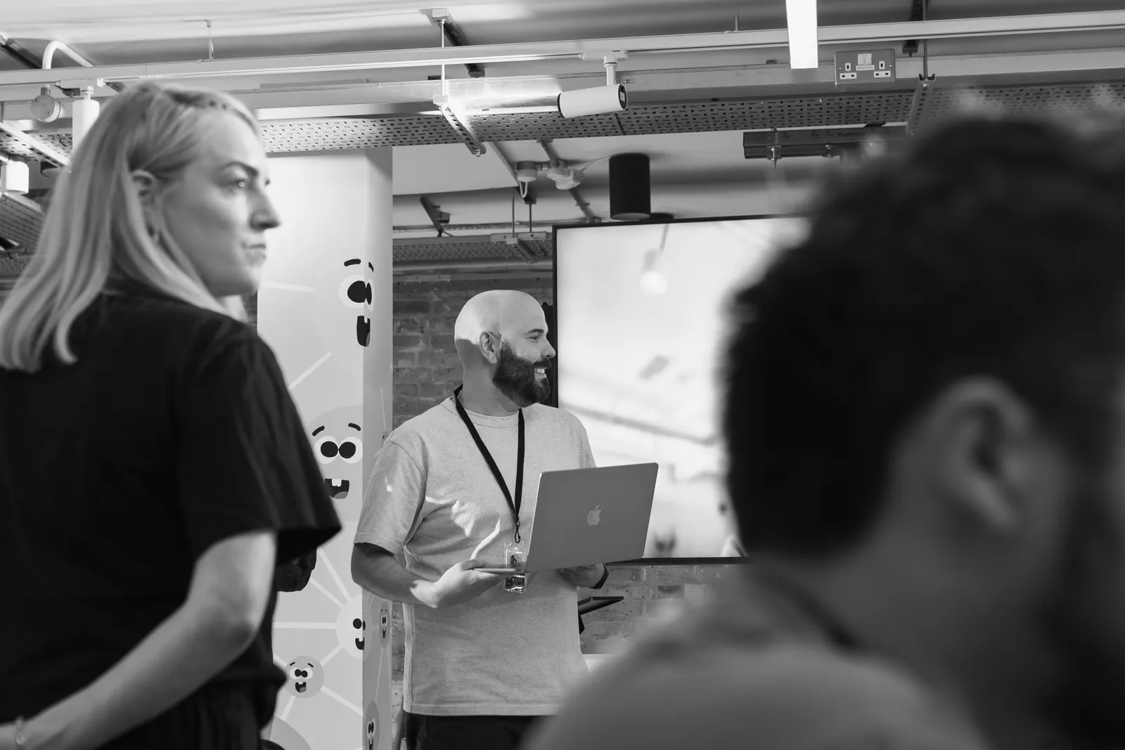 Presenter with a laptop speaking to a team seated around a meeting table