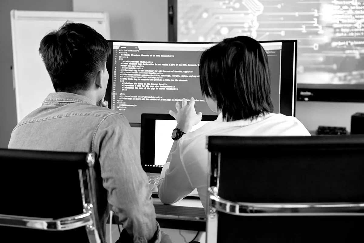 Two developers reviewing code together on a monitor