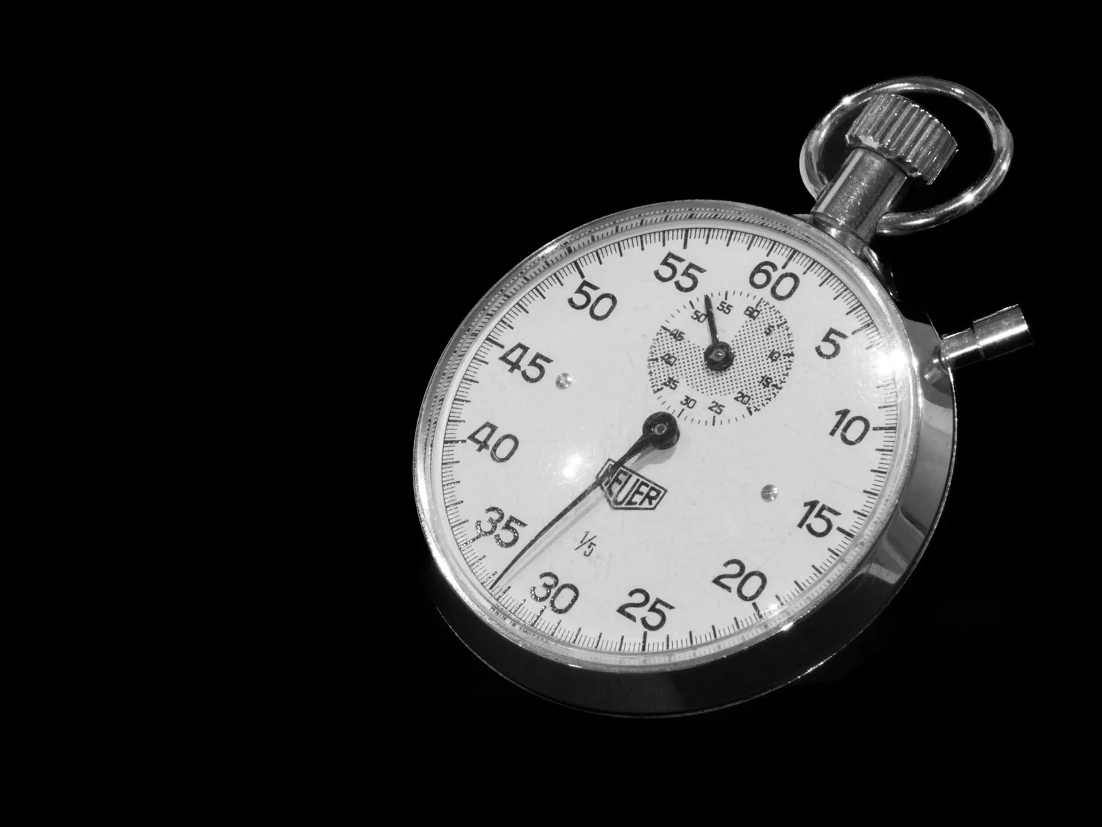 Vintage mechanical stopwatch with a black dial on a dark background