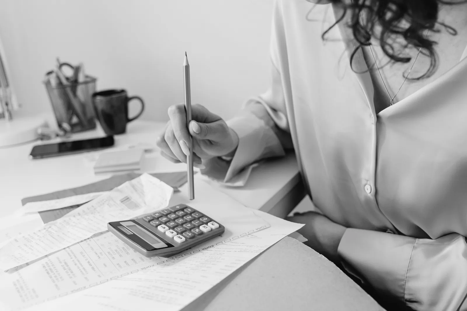 Woman working out expenses with a calculator and papers at her desk