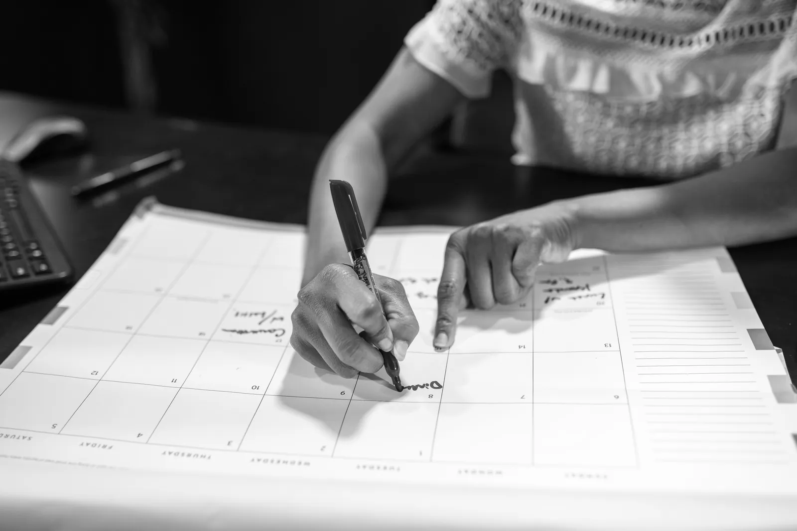 Woman marking dates on a paper desk calendar