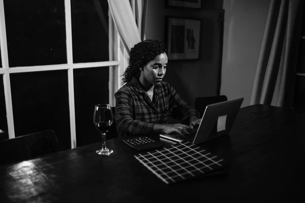 Woman working on a laptop at night in a dim room